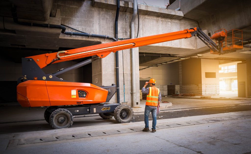 Safety worker operating articulated boom lift inside multi-level construction site-Boom Lift Training 