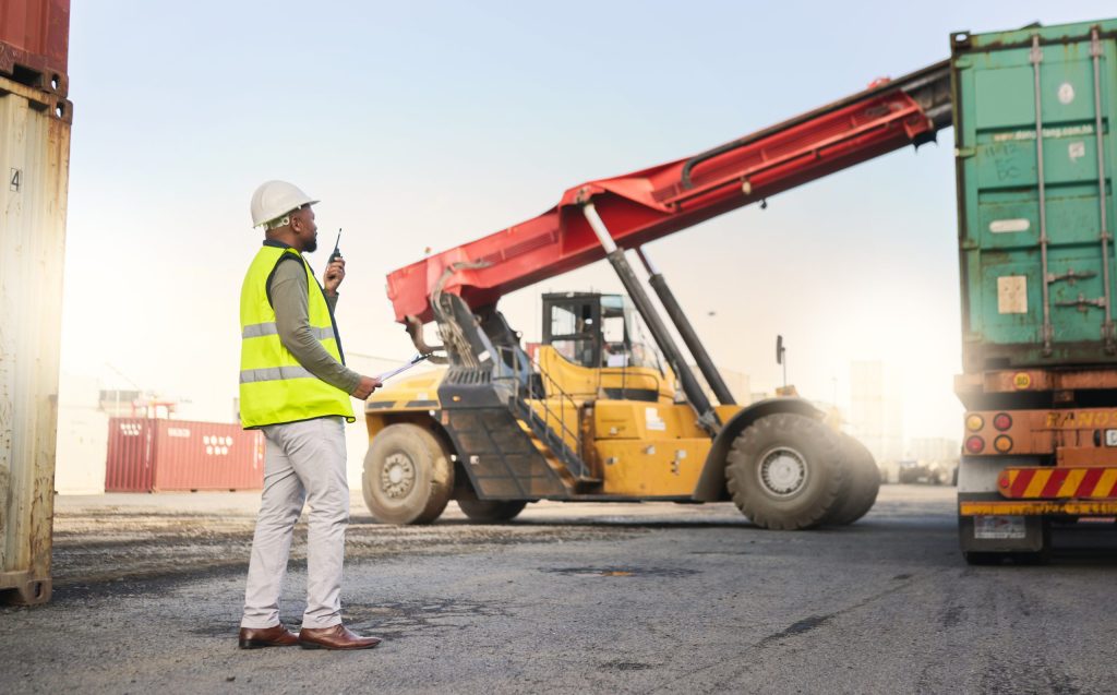 Port worker supervising container handling operations with yellow reach stacker-Rough Terrain Forklift Certification