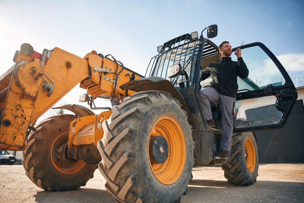 Construction worker operating yellow telehandler with safety cab at job site-Rough Terrain Forklift Certification