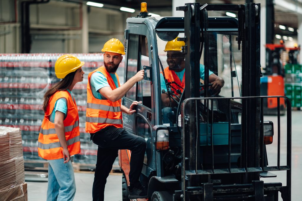 Forklift instructor coaching a trainee during Seat Time All Forklift Certification in a warehouse environment.
